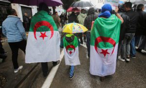 People wearing national flags march during a protest demanding political change, in Algiers