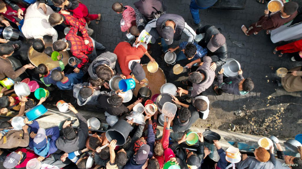 Palestinians gather to receive food cooked by a charity kitchen, in Rafah