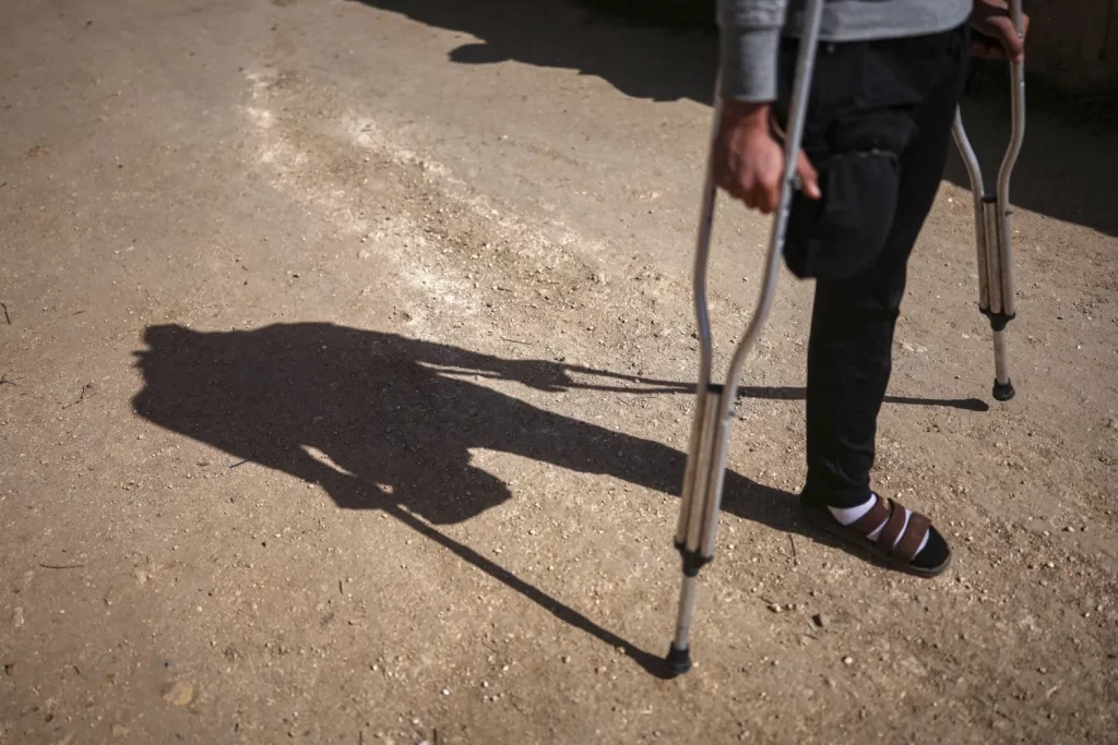 كان سليمان خليل منهمكاً في قطف الزيتون داخل بستان سوري، مع اثنين من أصدقائه قبل أربعة أشهر، دون أن يدرك أن التربة تحت أقدامهم لا تزال تخفي بقايا الحرب القاتلة. فجأة، لاحظ الثلاثة لغماً أرضياً ظاهراً على الأرض. انتابت حالة من الذعر الأصدقاء الثلاثة، وحاولوا مغادرة المكان سريعاً، لكن قدم خليل وطأت بالخطأ لغماً أرضياً فانفجر. ركض أصدقاؤه مرعوبين للبحث عن سيارة إسعاف، بينما ظن خليل، 21 عاماً، أنهم قد تركوه. قال خليل لوكالة «أسوشييتد برس»: «دأت بالزحف، ثم انفجر لغم ثانٍ»، مضيفاً: «في البداية، ظننت أنني متّ. لم أعتقد أنني سأنجو من هذا الموقف». أُصيب خليل في ساقه اليسرى إصابة بالغة في الانفجار الأول، بينما بُترت ساقه اليمنى من فوق الركبة في الانفجار الثاني. واستخدم قميصه لربط الجرح، وصرخ طلباً للمساعدة حتى سمعه جندي قريب وهرع لإنقاذه. قال خليل: «مرت علي أيام فقدت فيها رغبتي في الحياة». كان جالساً على فرشة رقيقة، وساقه المبتورة لا تزال ملفوفة بقطعة قماش بيضاء بعد أربعة أشهر من الحادث. خليل، من قرية قميناس في جنوب محافظة إدلب، مرتبط بعلاقة خطوبة، ويأمل في الحصول على طرف صناعي، ليعود إلى العمل، ويعول عائلته. رغم أن الحرب السورية التي استمرت نحو 14 عاماً انتهت بسقوط بشار الأسد في الثامن من ديسمبر (كانون الأول)، فإن بقايا الحرب لا تزال تفتك بالناس قتلاً، وتشويهاً. وتكشف الأرقام الصادرة عن منظمة «آي إن إس أو»، المعنية بالسلامة، أن الألغام والمتفجرات قتلت ما لا يقل عن 249 شخصاً، بينهم 60 طفلاً، وأصابت 379 آخرين منذ الثامن من ديسمبر، تاريخ سقوط نظام الأسد. استخدمت القوات الحكومية السورية وحلفاؤها، إلى جانب جماعات من المعارضة المسلحة، الألغام منذ عام 2011، ما أدى إلى تلوث مساحات شاسعة بها، كثير منها لم يكن متاحاً الدخول إليها سوى بعد انهيار حكومة الأسد، الأمر الذي تسبب في تفاقم أعداد ضحايا الألغام، وفقاً لتقرير حديث صادر عن منظمة «هيومان رايتس ووتش». يذكر أنه قبل الثامن من ديسمبر، كانت الألغام وبقايا الحرب تتسبب كذلك في إصابات ووفيات متكررة للمدنيين العائدين إلى منازلهم، أو إلى أراضيهم الزراعية. في هذا الصدد، قال ريتشارد وير، كبير الباحثين بمجال الأزمات والصراعات لدى «هيومان رايتس ووتش»: «دون جهود تطهير عاجلة على مستوى البلاد، سيكون هناك المزيد من المدنيين العائدين لاستعادة حقوقهم وحياتهم وسبل عيشهم، وأراضيهم على موعد مع الإصابة أو الموت». ويقدّر خبراء أن عشرات الآلاف من الألغام لا تزال مدفونة بأرجاء سوريا، خصوصاً في المناطق التي كانت خطوط مواجهة سابقة، مثل ريف إدلب. وقال أحمد جمعة، عضو في وحدة إزالة الألغام، التابعة لوزارة الدفاع السورية: «لا نعرف العدد الدقيق للألغام، وسيستغرق الأمر سنوات للتخلص منها كلها». جاء حديث جمعة بينما كان يمشط أراضي زراعية شرق معرة النعمان بجهاز كشف يدوي، مشيراً إلى لغم مضاد ظاهر في التربة الجافة. وقال: «هذا اللغم يمكنه أن يبتر ساقاً. علينا تفجيره يدوياً». من ناحية أخرى، تبقى الزراعة المصدر الرئيس للدخل في ريف إدلب، ما يجعل وجود الألغام تهديداً يومياً. قبل أيام فقط، انفجر جرار زراعي قريب، ما أدى إلى إصابة عدد من العمال بجروح خطيرة، بحسب جمعة. ونبه إلى أن: «معظم الألغام هنا مصممة لاستهداف الأفراد والمركبات الخفيفة، مثل تلك التي يستخدمها الفلاحون». من ناحيتها، بدأت الوحدة التي يعمل فيها جمعة تفكيك الألغام مباشرة بعد سقوط الحكومة السابقة، لكن ذلك أتى بثمن باهظ. وعن ذلك قال: «خسر ما بين 15 إلى 20 من زملائنا أطرافهم، وسقط نحو عشرة من إخوتنا قتلى أثناء العمل». وأضاف أن أجهزة الكشف المتقدمة، التي تكشف الألغام المدفونة أو الأجهزة المُعدلة، نادرة. وفي الوقت الذي لا تزال بعض الألغام مرئية للعين المجردة، فإن البعض الآخر أكثر تطوراً، ويصعب اكتشافه. تجدر الإشارة إلى أن آثار الألغام لا تقتصر على القتل والتشويه، بل تتسبب كذلك في صدمة نفسية طويلة الأمد، وأضرار أوسع، مثل التهجير، وفقدان الممتلكات، وتقييد الوصول إلى الخدمات الأساسية، بحسب «هيومان رايتس ووتش». المنظمة الحقوقية حثت الحكومة السورية الانتقالية على إنشاء هيئة بقيادة مدنية تعنى بالتخلص من الألغام، وبالتنسيق مع دائرة الأمم المتحدة للإجراءات المتعلقة بالألغام، توسيعاً لنطاق جهود التخلص من الألغام. جدير بالذكر أن القوات المسلحة السورية في عهد الأسد زرعت الألغام لردع مقاتلي المعارضة. وحتى بعد استعادة المناطق القريبة، لم تبذل الحكومة جهداً يُذكر للتخلص منها. أمام قبر شقيقه، وقف صلاح سويد رافعاً صورة على هاتفه تُظهر محمد مبتسماً خلف كومة من الألغام المُفككة. قال صلاح: «أمي، مثل أي أم، حذرته من الذهاب، لكنه قال: إذا لم أذهب أنا ولم يذهب غيري، فمن سيذهب؟ كل يوم هناك من يموت». كان محمد في الـ39 من عمره عندما قضى في 12 يناير (كانون الثاني)، أثناء تفكيك الألغام في إحدى قرى إدلب. وكان عضواً سابقاً في الحرس الجمهوري السوري، وتلقى تدريباً على زرع الألغام وتفكيكها.